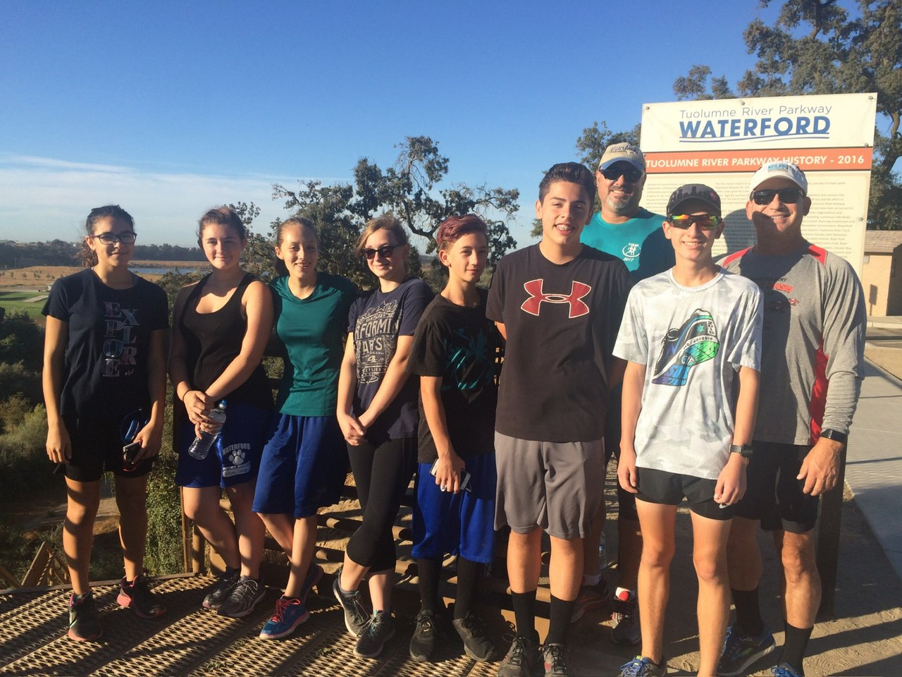Todd Valdez with a group of runners in front of a Tuolumne River Parkway Waterford sign.